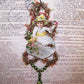 Victorian Revival handcrafted tinsel and mercury glass Christmas ornament.  Die cut of a Lady in white holding flowers is the focal point. Light but lengthy.