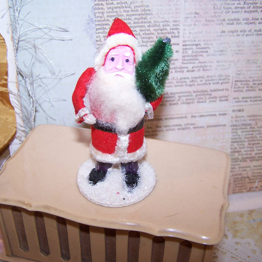 Vintage Made in Japan Santa Claus Christmas figure decoration.  Pink clay face, Santa wears felt-like clothing and carries a tree of green chenille.