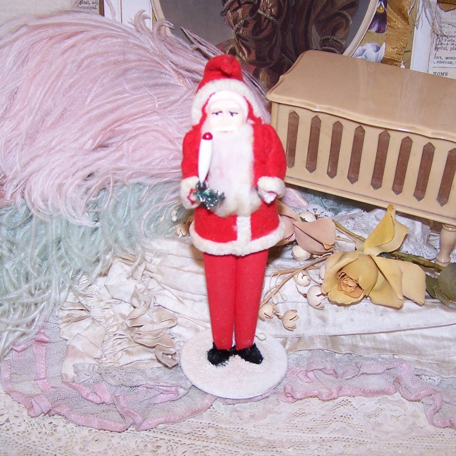 Vintage Made in Japan stand-up Santa Claus.  Hard plastic face, the gent wears felt-like clothing with a chenille edge. He carries a candle and sprig of green.