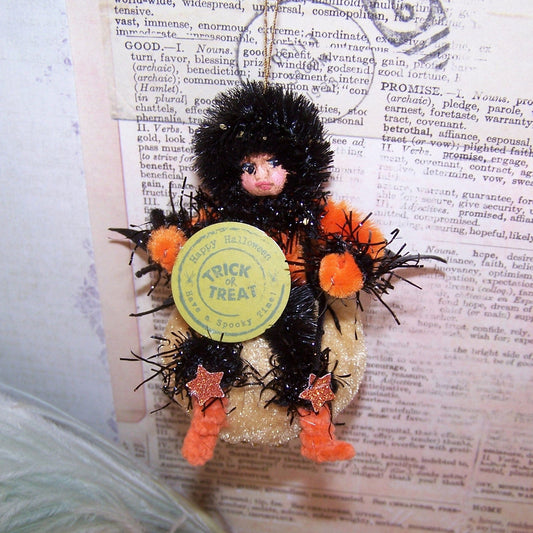 Mixed media OOAK Halloween ornament of a little girl carrying a Trick or Treat sign while sitting on a velvet pumpkin.  Handpainted face.  3-3/4" x 2-1/2"
